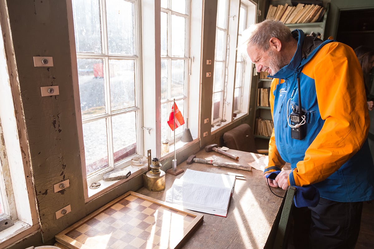 Geologist and expedition guide Michael Hambrey reads through the logbook of the historic hut at Ella Island. Photo by Acacia Johnson