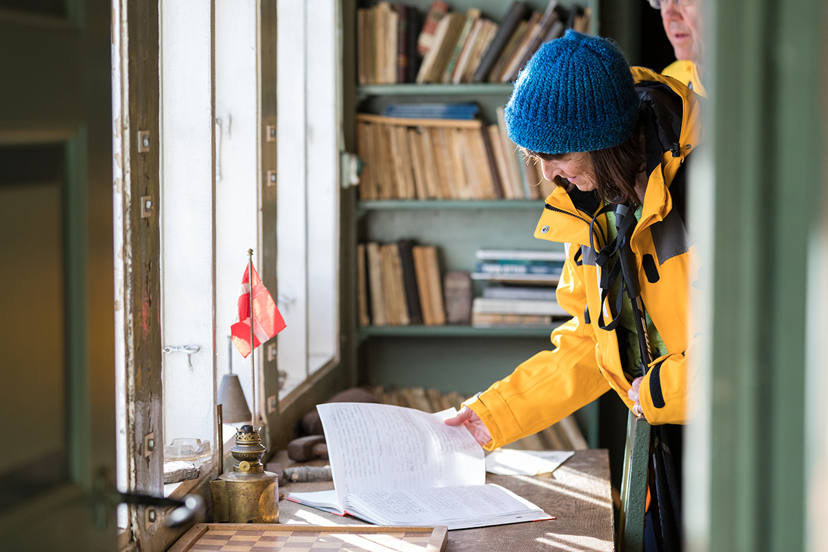 Quark Expeditions passenger reviews the log of visitors who have passed through over time. Photo: Acacia Johnson