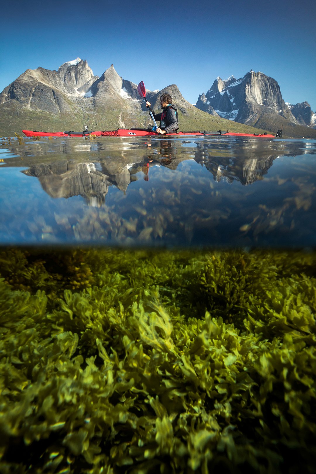 A kayaker paddles past towering spires of ancient rock in the 70-km long Tasermiut Fjord in South Greenland.